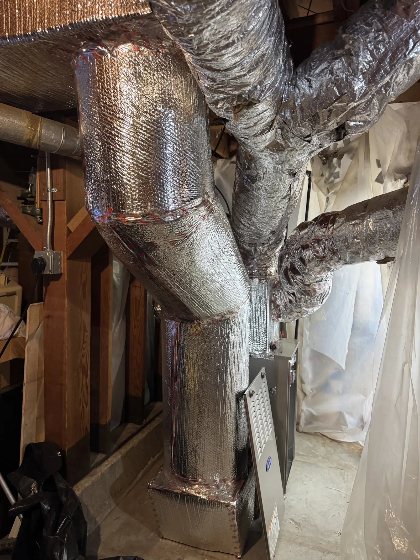 Insulated radial supply trunk feeding multiple flex branches above a Carrier furnace during a Westside Los Angeles ductwork retrofit